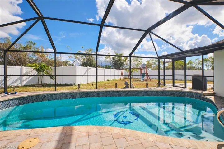 Another view of the pool overlooking the fenced in yard.  Pool heater is being removed as it does not work.  Re-surfaced pool complete with swimming dophins!  Playground stays if new buyers wish.