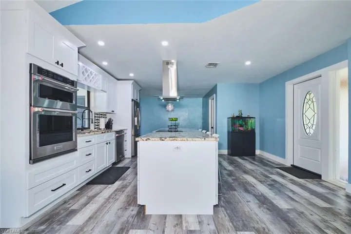 Another view of the kitchen.  Custom cabinets, wall oven, overhead exhaust fan, smooth top stove and room to seat four comfortably at the island.    Granite countertops, large deep sink, wine rack and window overlooking the pool and HUGE yard.