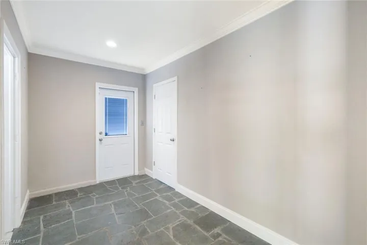Tiled spare room featuring crown molding