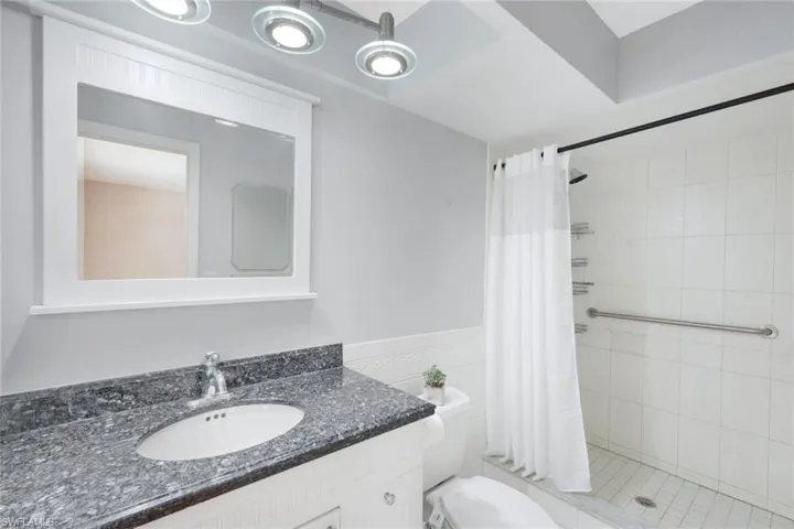 Bathroom with curtained shower, vanity, and toilet