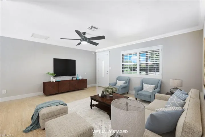 Living room with ornamental molding, ceiling fan, and light wood-type flooring