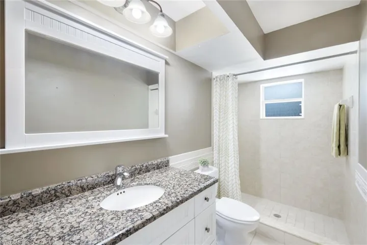 Bathroom with vanity, tile patterned flooring, a shower with shower curtain, and toilet