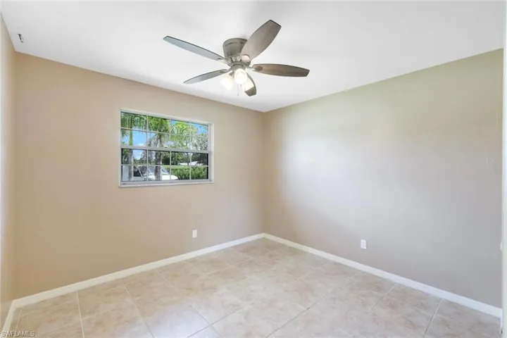 Tiled spare room featuring ceiling fan
