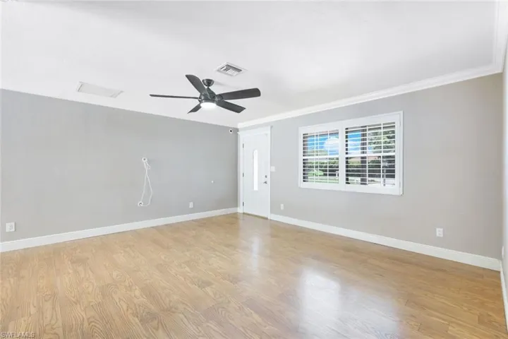 Empty room with ceiling fan, light hardwood / wood-style flooring, and ornamental molding
