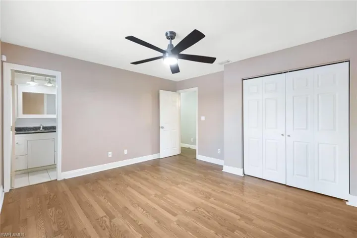 Unfurnished bedroom featuring light hardwood / wood-style flooring, a closet, ensuite bath, and ceiling fan