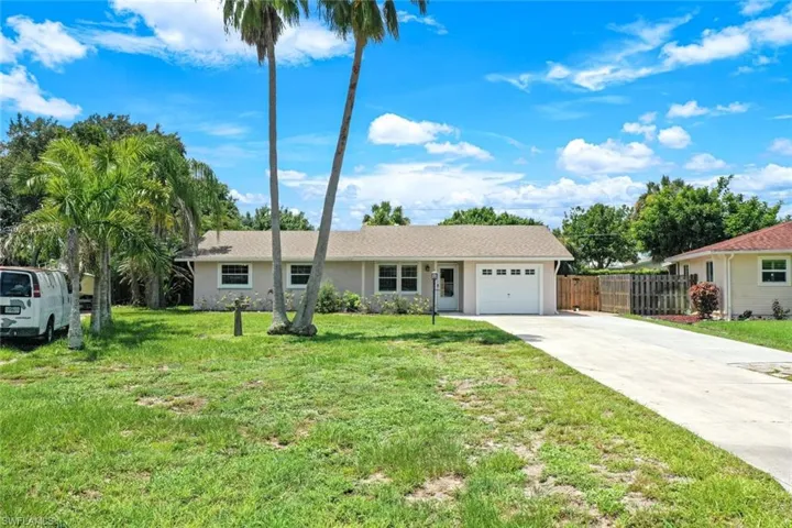Ranch-style home featuring a garage and a front lawn