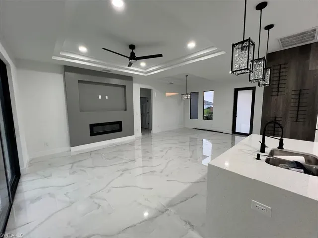 Tiled living room featuring ceiling fan and a raised ceiling