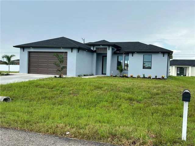 View of front facade featuring a garage and a front lawn
