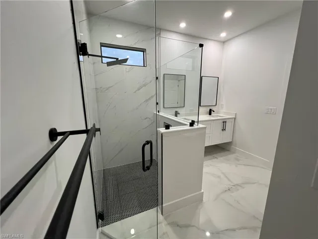 Bathroom featuring tile floors, walk in shower, and vanity