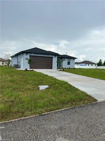 Ranch-style home featuring a garage, a front yard, and central AC