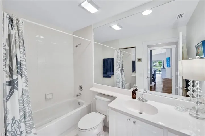 Bathroom featuring a white vanity with integrated sink, a large wall-mounted mirror, a bathtub with white subway tile surround, and recessed lighting