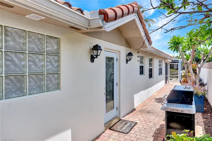 Exterior stucco finish with a terra cotta tile roof, glass block window, double-paned windows, and a paver walkway