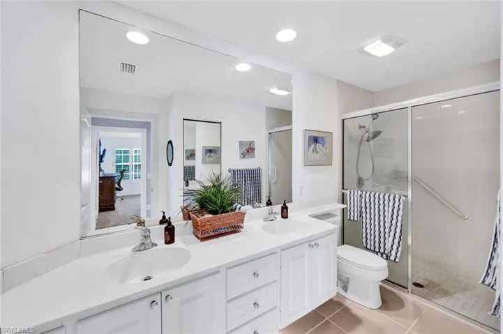 Bathroom featuring a dual vanity with white cabinetry, integrated sinks, and a full-width mirror