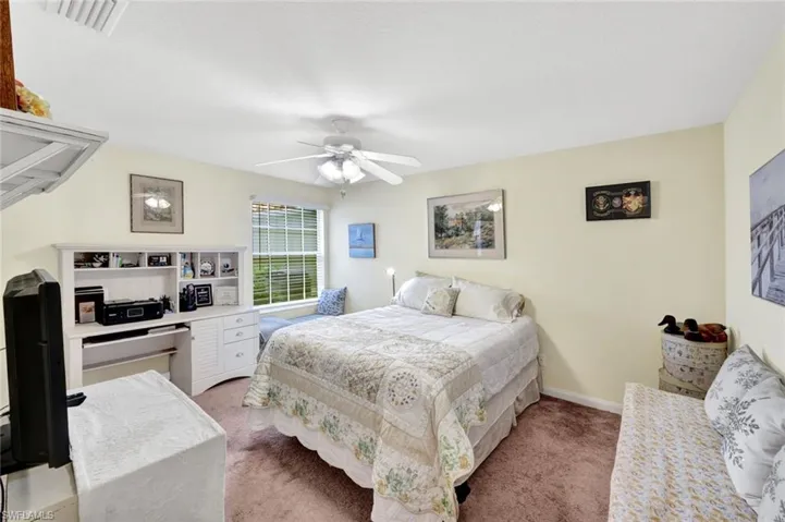 Carpeted room featuring a ceiling fan, a window with blinds, and a built-in desk unit with shelving and drawers