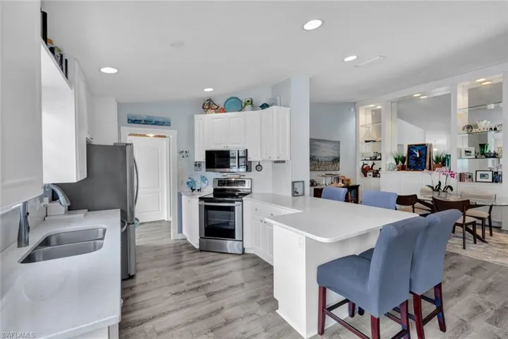 Contemporary kitchen featuring white cabinetry, stainless steel appliances, light-toned countertops, and wood-finish flooring