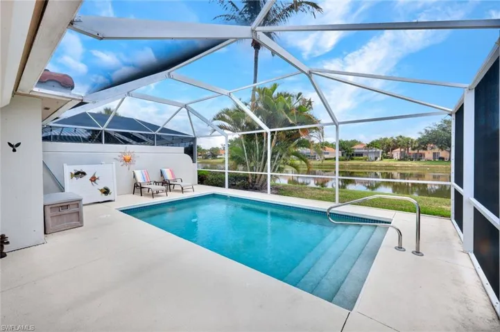 Screened-in swimming pool enclosure featuring a concrete patio, integrated pool steps, and a metal handrail