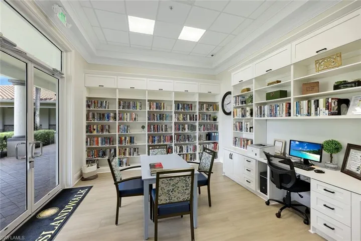 Library space featuring extensive built-in white shelving, wood-finish flooring, and crown molding