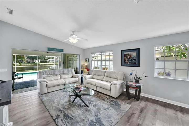 Living area featuring wood-finish flooring, vaulted ceilings, and a ceiling fan