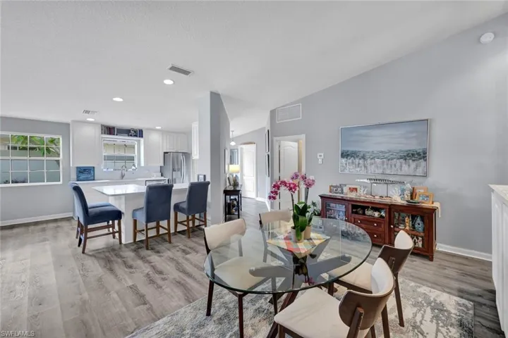 Open-concept living area with wood-finish flooring, vaulted ceilings, and recessed lighting