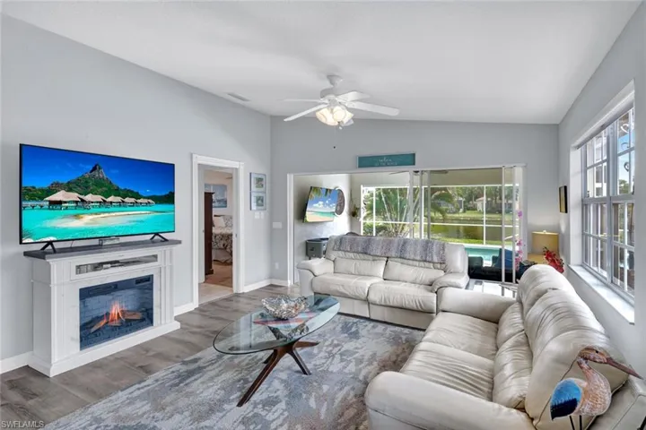 Living area featuring wood-finish flooring, a decorative fireplace, and a ceiling fan