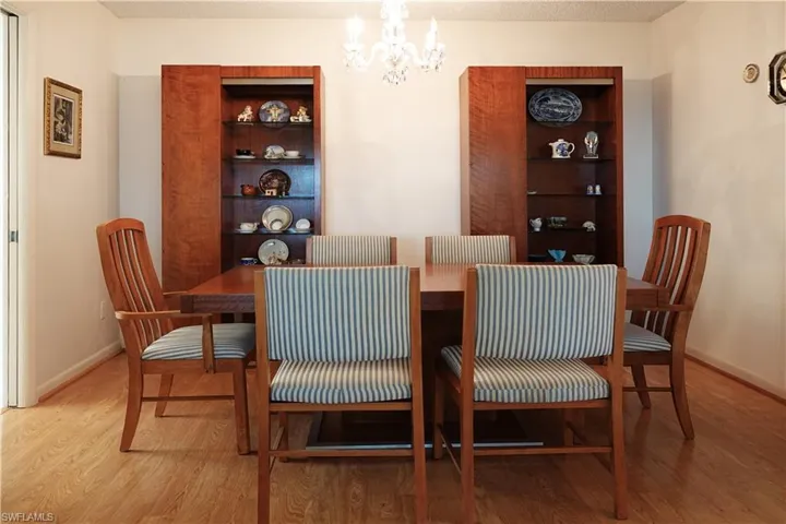 Dining room featuring wood finished floors, an inviting chandelier, and baseboards