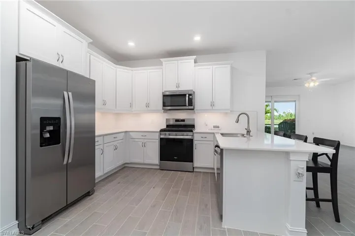 Kitchen featuring stainless steel appliances, a peninsula, a breakfast bar area, light countertops, and recessed lighting