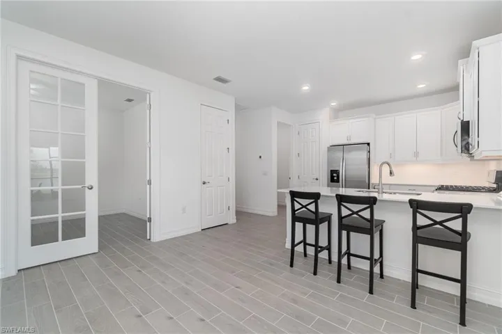 Kitchen featuring appliances with stainless steel finishes, a peninsula, light countertops, a breakfast bar area, and white cabinets