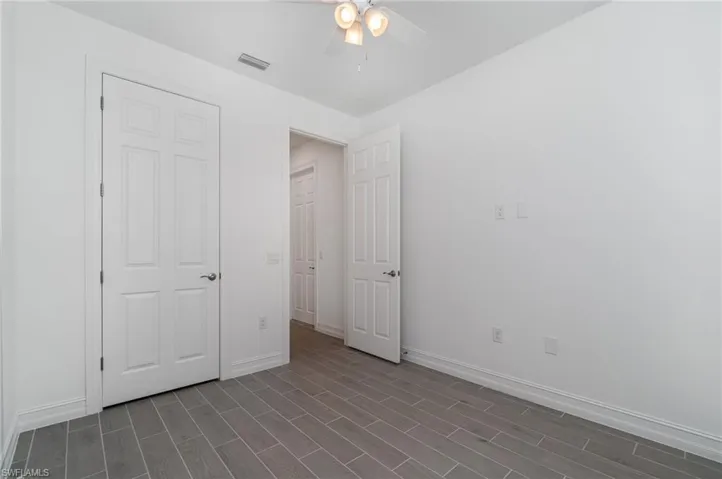 Unfurnished bedroom featuring dark wood finished floors and ceiling fan