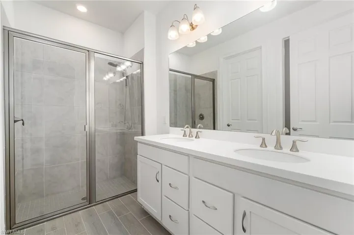 Full bath featuring double vanity, a stall shower, and recessed lighting