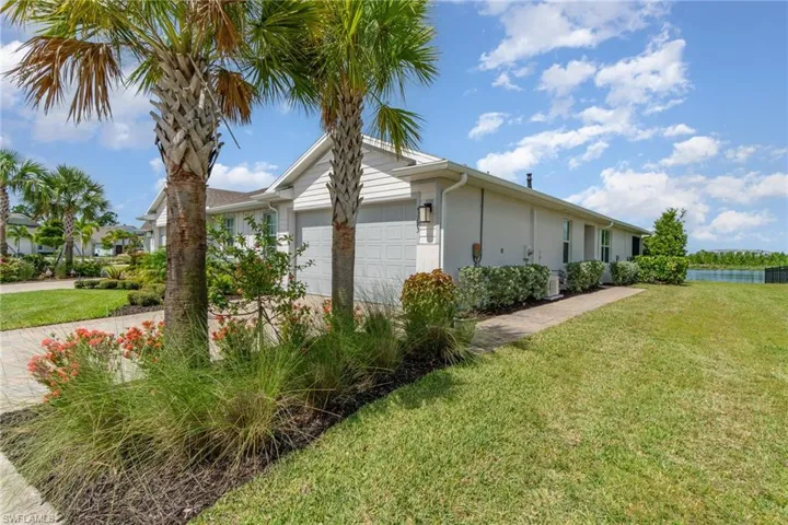 View of property exterior with an attached garage, a yard, driveway, and a water view
