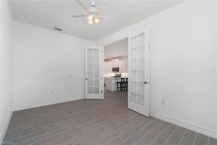 Spare room featuring french doors, dark wood-style floors, and a ceiling fan