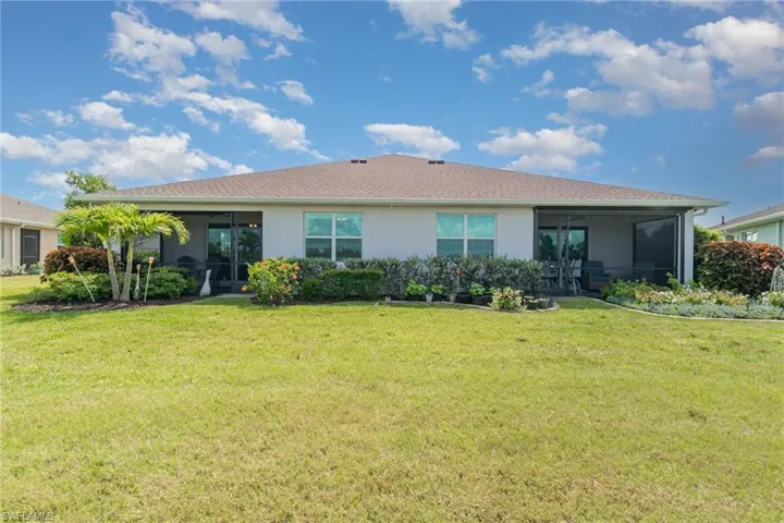 Back of house featuring a sunroom, stucco siding, and a lawn