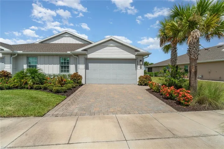 Single story home with an attached garage, a front yard, driveway, and board and batten siding