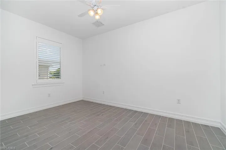 Empty room featuring dark wood finished floors and a ceiling fan