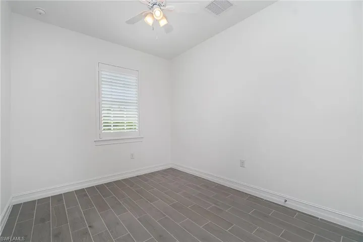 Empty room with ceiling fan, dark wood-style floors, and a smoke detector