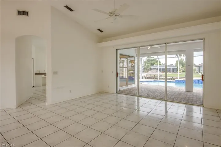 Tiled Living Room featuring ceiling fan and high vaulted ceiling, views to the Pool and Water with Triple Sliders