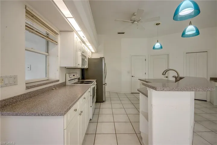 Kitchen with white cabinetry, light tile patterned floors, double oven range, and ceiling fan