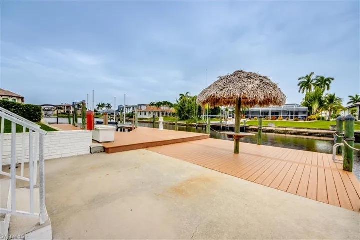 View of property's community with a boat dock and a water view, YOUR OWN TIKI HUT !  TREX DECKING, PILING CAPS, ELECTRICAL TOWER, LADDER, DECK BOX, BOAT LIFT!