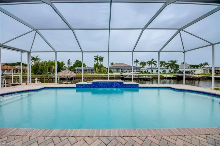 View of swimming pool with a dock, pool water feature, and Screened Enclosure
