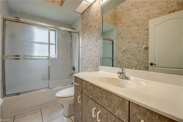 Full bathroom #2 featuring vanity, toilet, bath / shower combo with glass door, and tile patterned floors