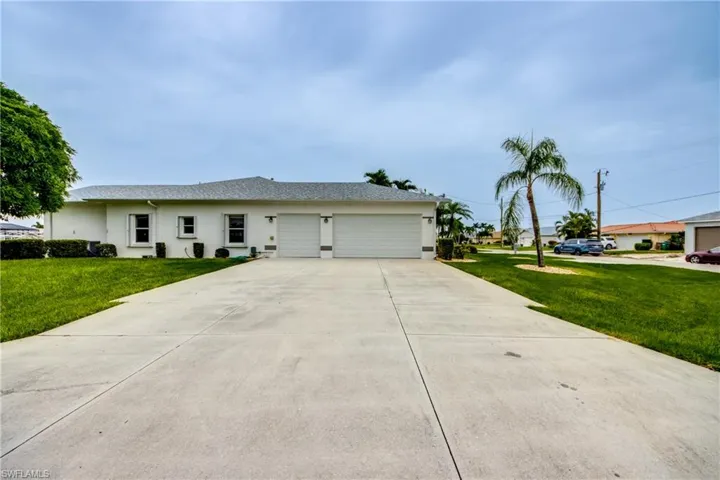 Single story home featuring a garage and a front lawn, SIDE LOAD GARAGE, two large driveways, manual Hurricane Shutters on side windows