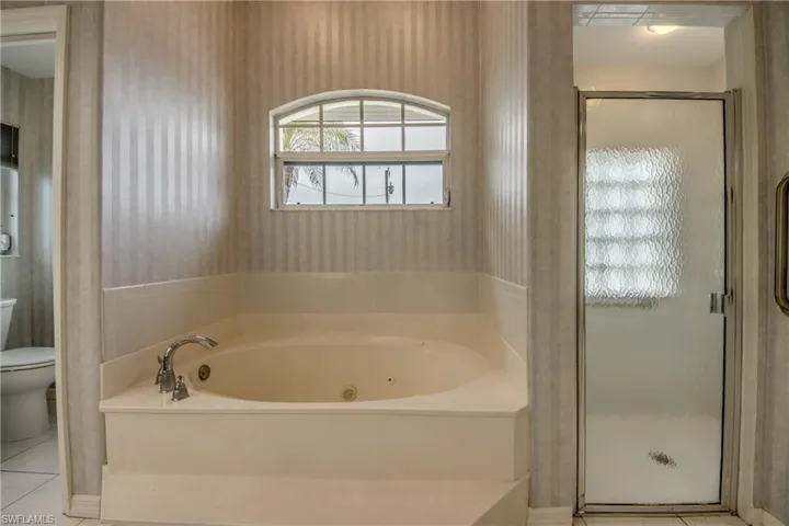 Bathroom with toilet, separate shower and tub, and tile patterned flooring