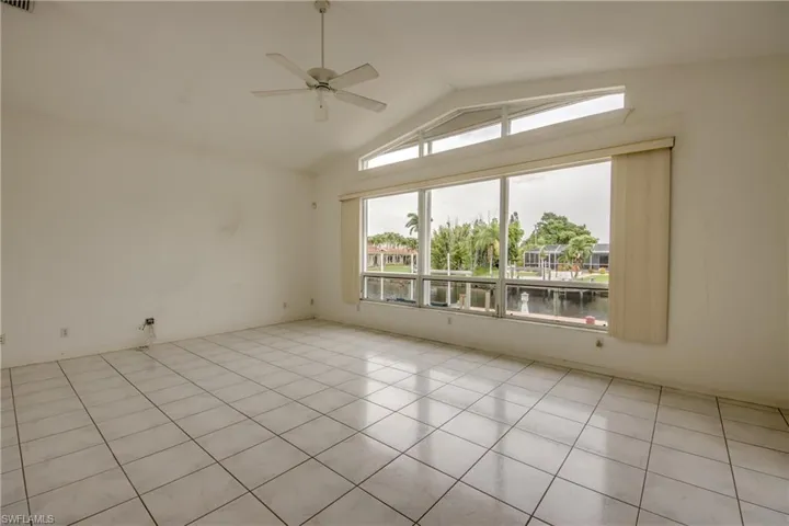 Family room with a water view, ceiling fan, vaulted ceiling, and light tile patterned floors
