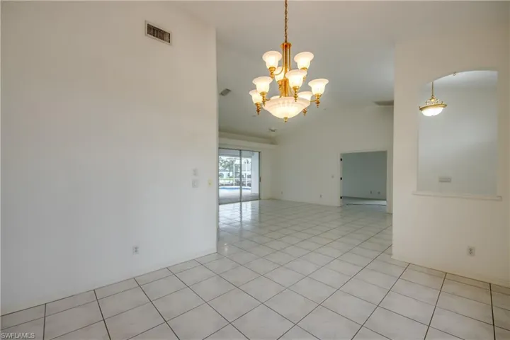 Unfurnished room featuring a chandelier, vaulted ceiling, and light tile patterned floors