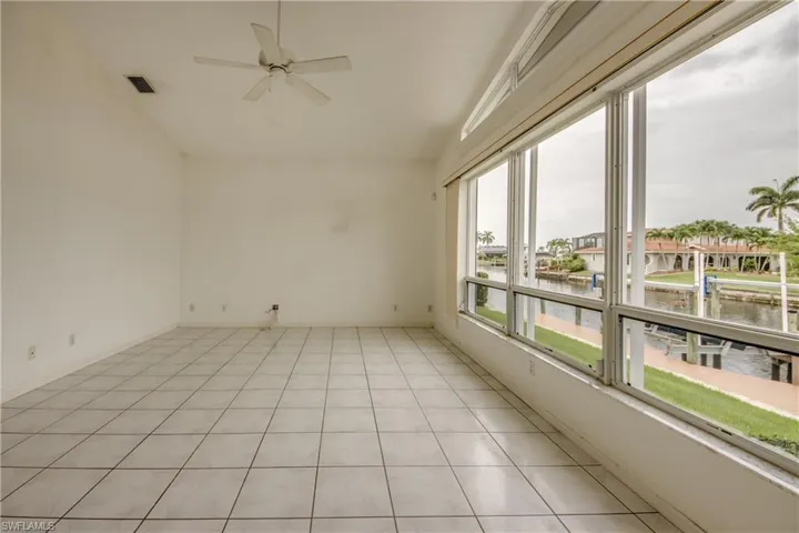 Family room with lofted ceiling, a water view, light tile patterned floors, and ceiling fan