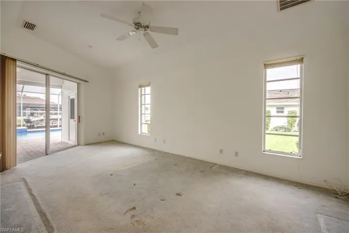 Master Bedroom with carpet floors, a healthy amount of sunlight, and ceiling fan.  Sliding Glass Doors lead to view of water and pool.