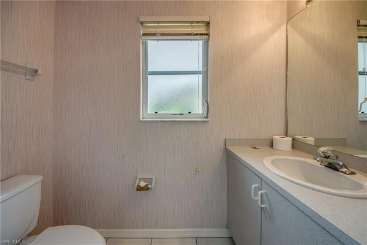POOL BATH WITH ENTRY DOOR IN LANAI !!  Bathroom featuring tile patterned floors, toilet, and vanity