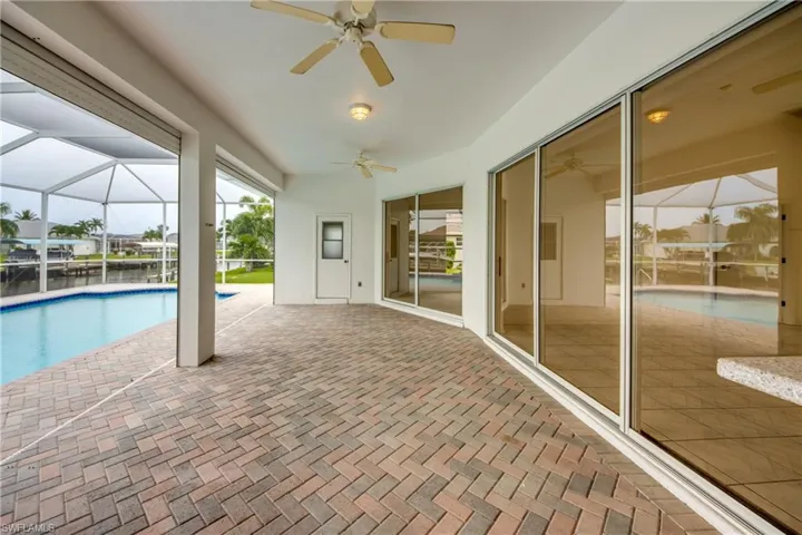 View of swimming pool with SCREENED enclosure, a patio area, and ceiling fan.  Door with window leads to Pool Bathroom