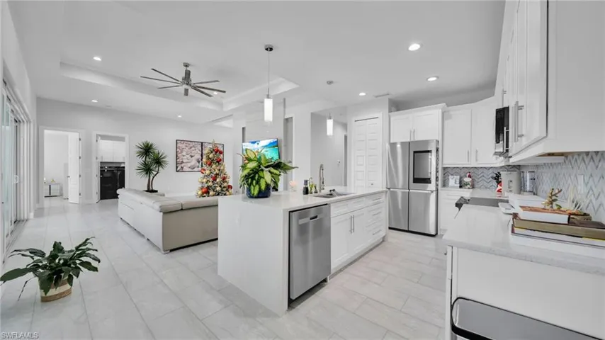 Kitchen with open floor plan, appliances with stainless steel finishes, a tray ceiling, white cabinetry, and recessed lighting