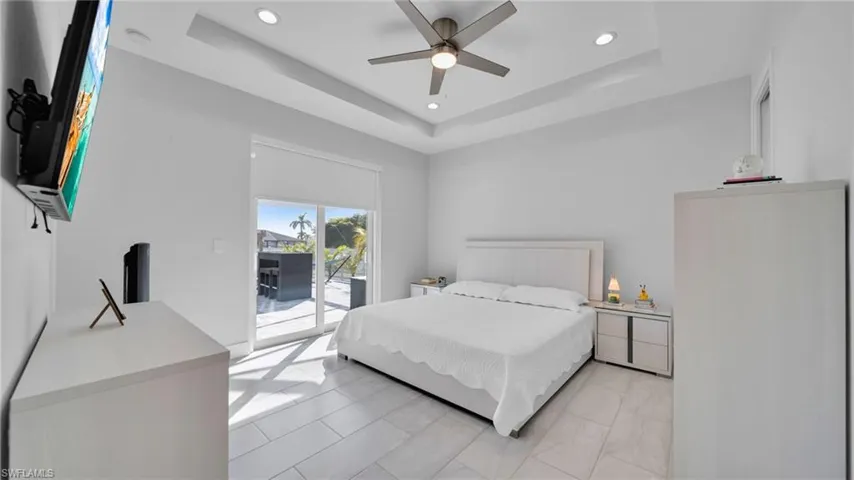Bedroom featuring access to exterior, ceiling fan, recessed lighting, and a tray ceiling